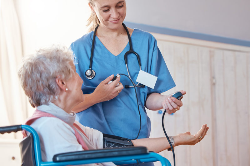 hospice patient with nurse taking blood pressure